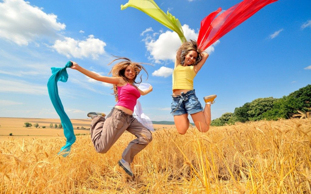 Two teenagers jumping for joy in a golden field